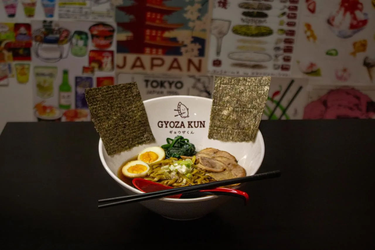 Ramen de la casa frente al mural de carteles japoneses del local